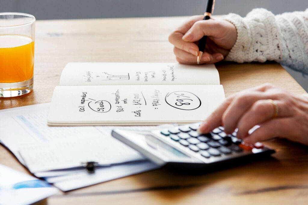 woman writing in a notebook and using a calculator