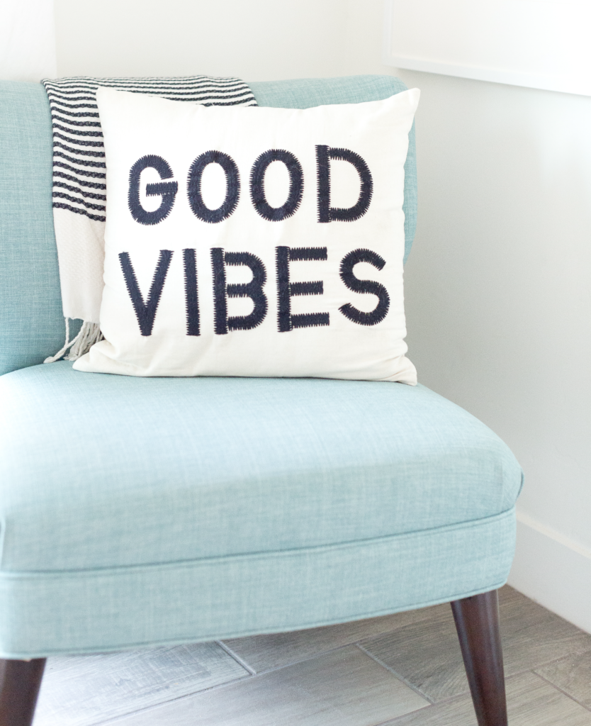 image of a blue chair with a white pillow on it. Words "Good Vibes" in black letters on the pillow