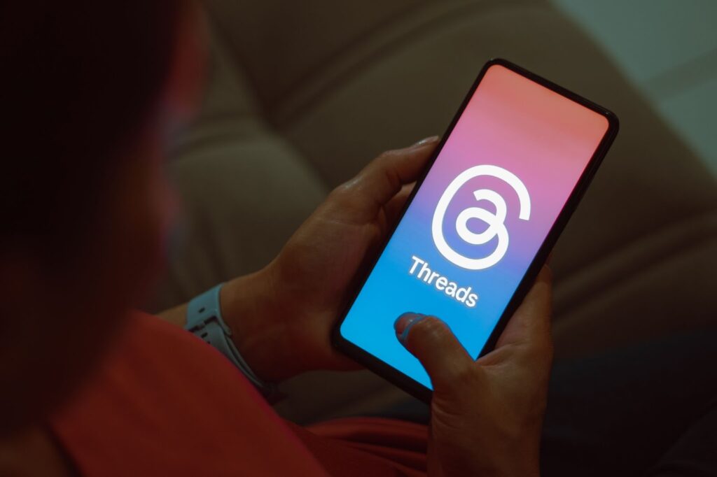 person holding a cell phone displaying the Instagram Threads logo on the screen